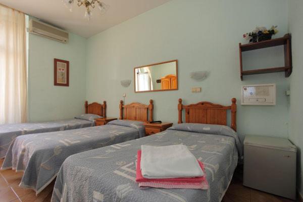 Habitación con 2 camas y espejo. en Hostal Fuentesol, en Madrid