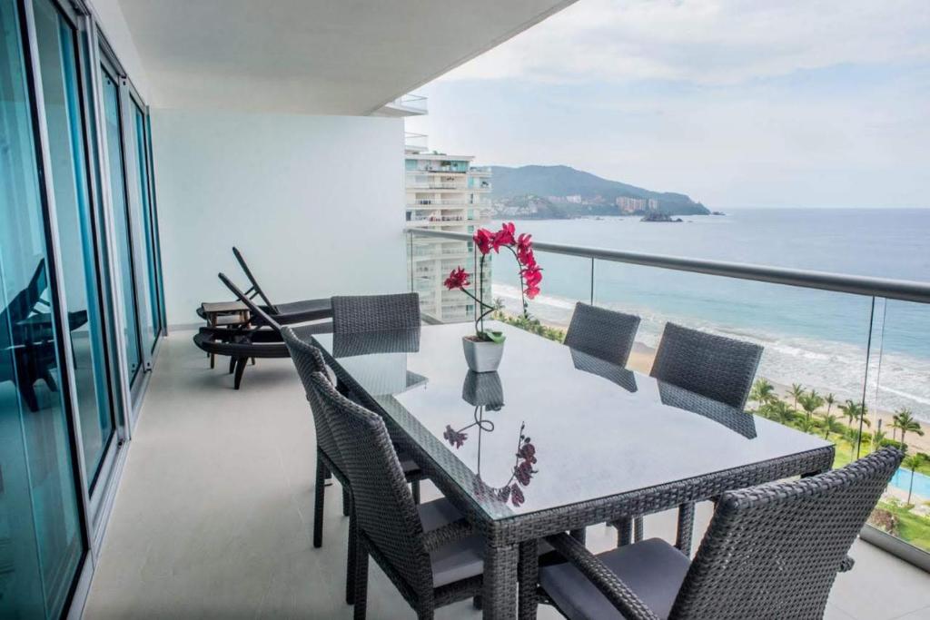y balcón con mesa de comedor y sillas y vistas al océano. en PENINISULA ViSTA AL MAR BY ENNA INN IXTAPA, en Ixtapa