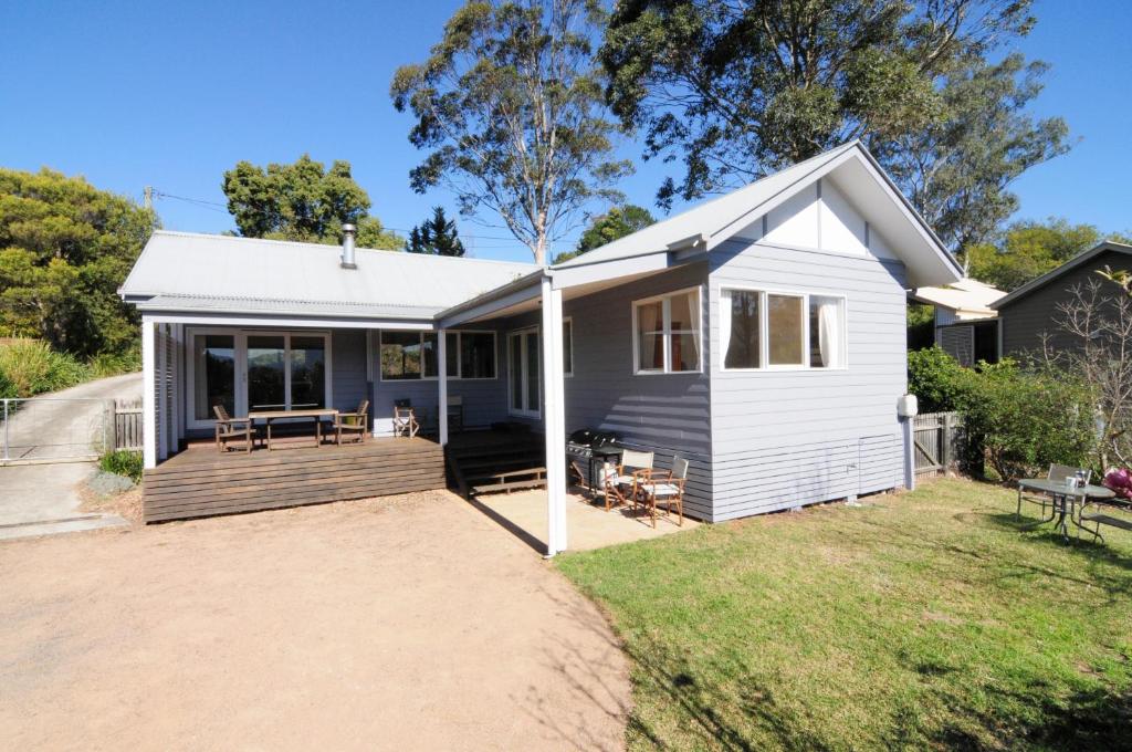 a small white house with a deck at Bimbadeen Comfortable country styled house in Kangaroo Valley