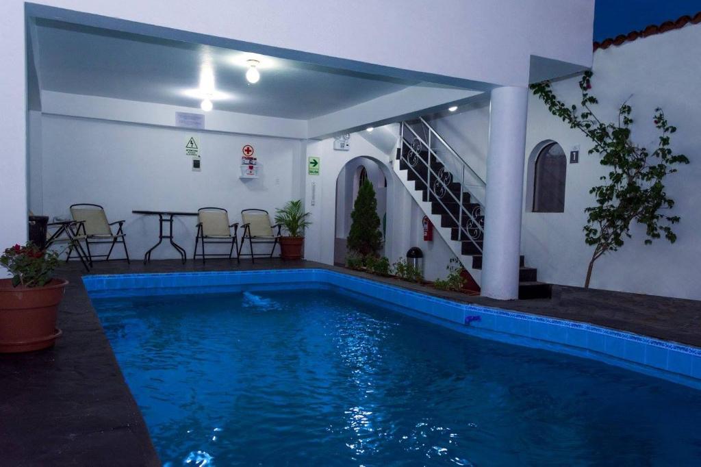 a swimming pool in a house with a table and chairs at Hotel Via Morburg in Nazca