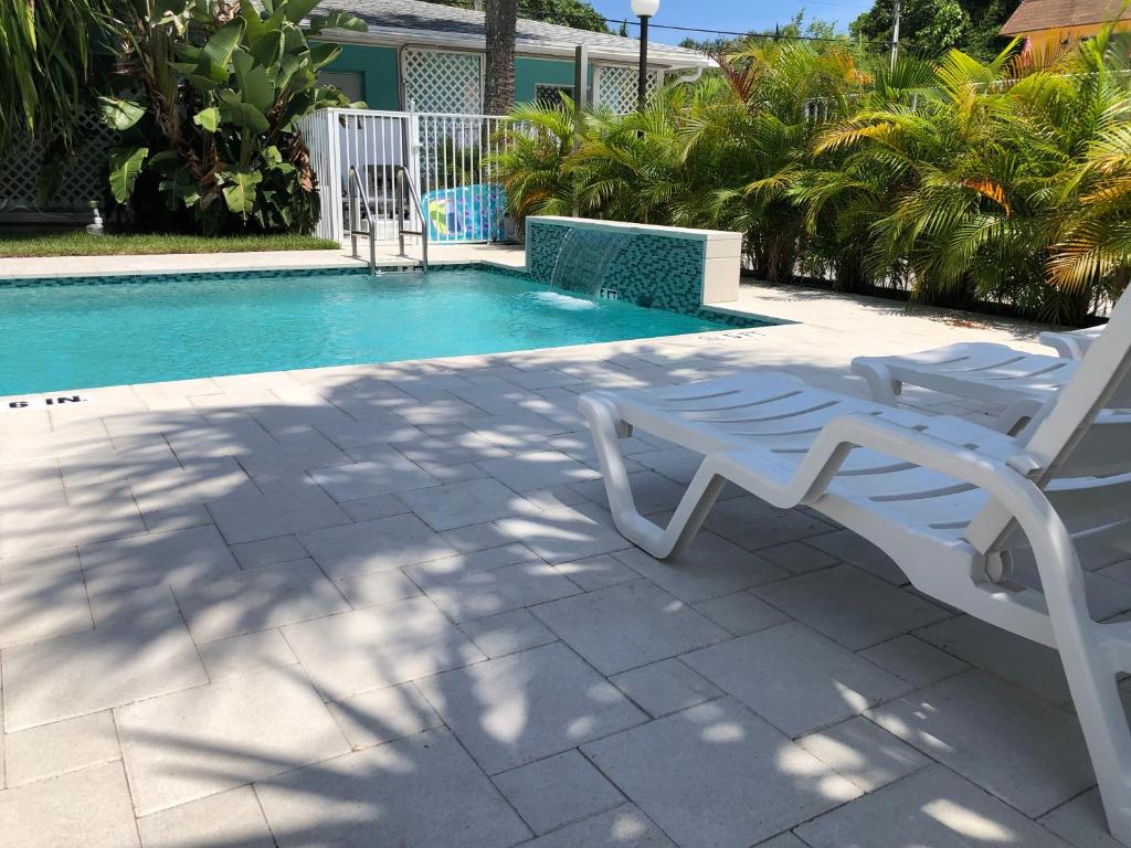 a white chair sitting next to a swimming pool at White Horse Motel in Lake Worth