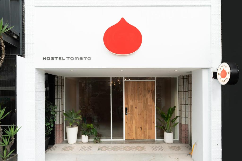 a front door of a hotel with a red sign at Hostel Tomato 番茄溫泉青旅 in Jiaoxi