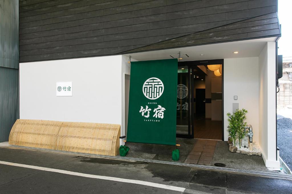 a green sign on the side of a building at Hostel Takeyado in Osaka