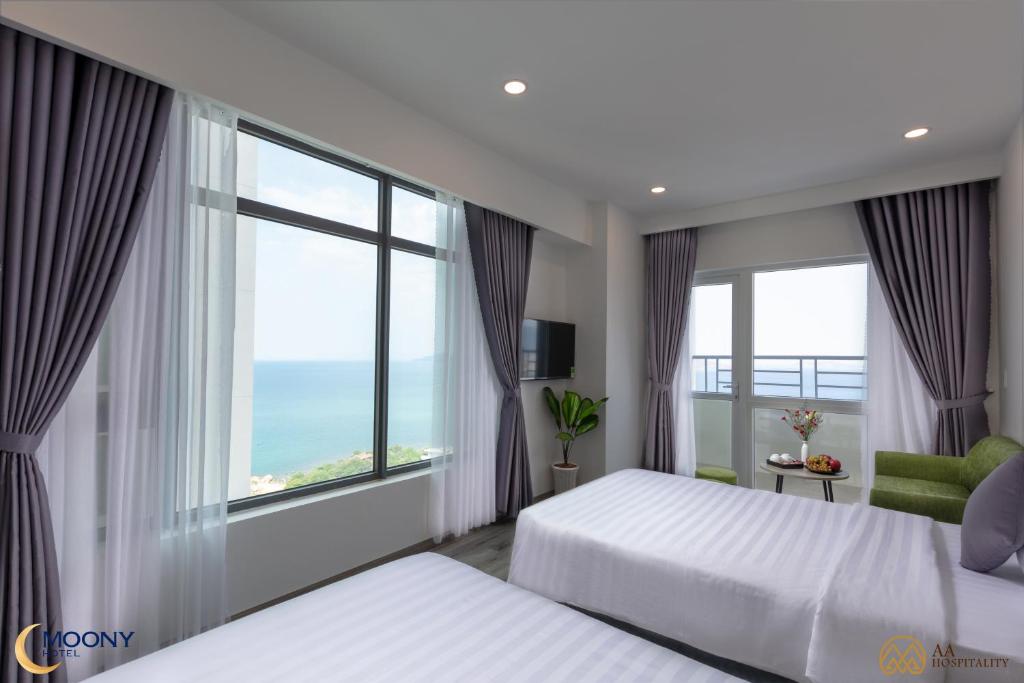 a bedroom with two beds and a large window at Nha Trang Moony Hotel in Nha Trang