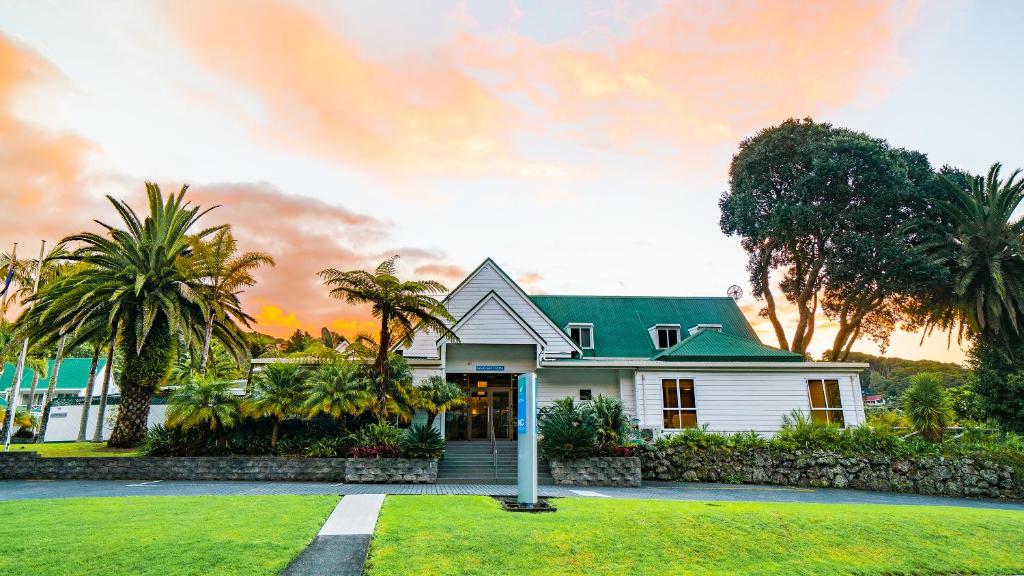 a white house with a green roof and palm trees at Scenic Hotel Bay of Islands in Paihia