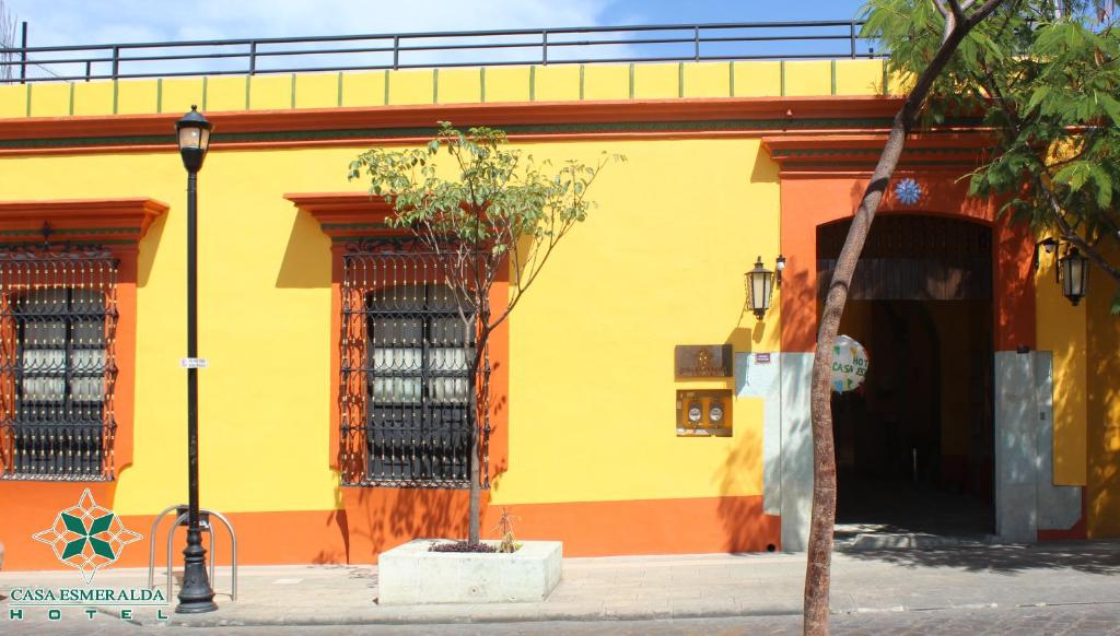 a yellow and orange building with a tree in front of it at Casa Esmeralda Hotel in Oaxaca City