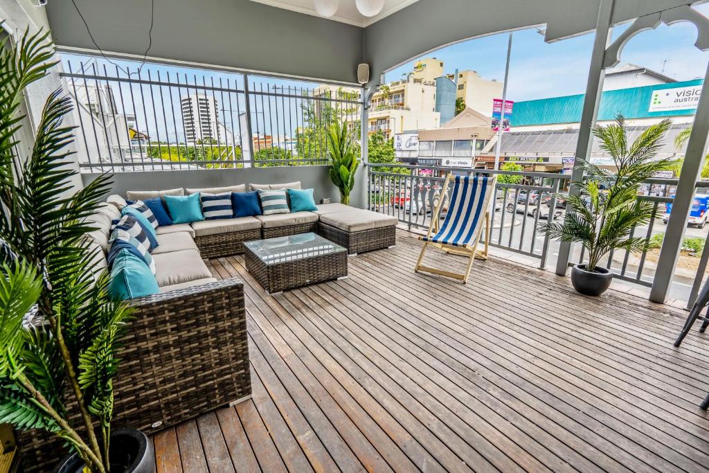 een patio met een bank en stoelen op een balkon bij The Village Cairns in Cairns