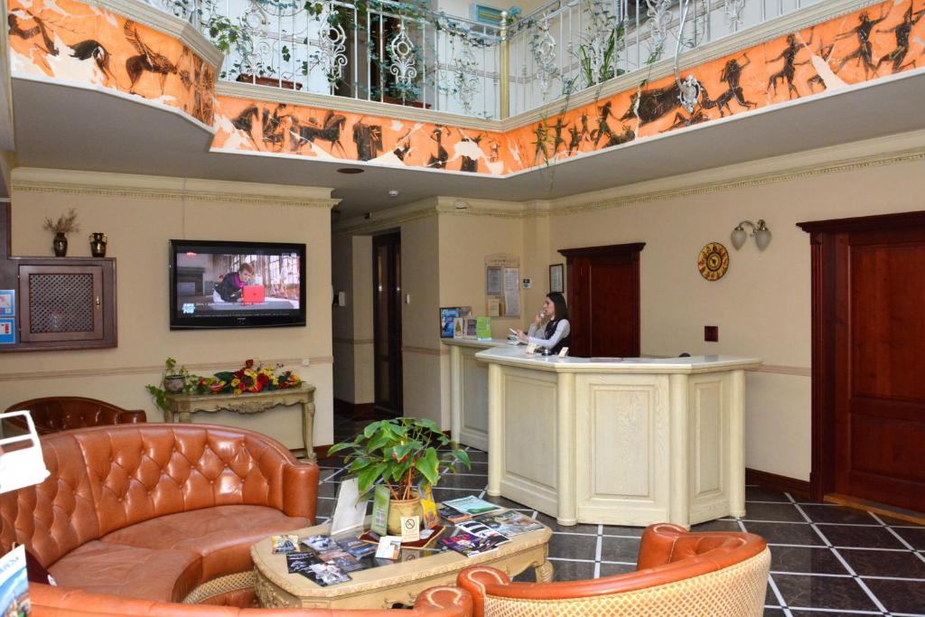 a lobby with a woman sitting at a counter at Atrium Hotel in Ivano-Frankivsʼk