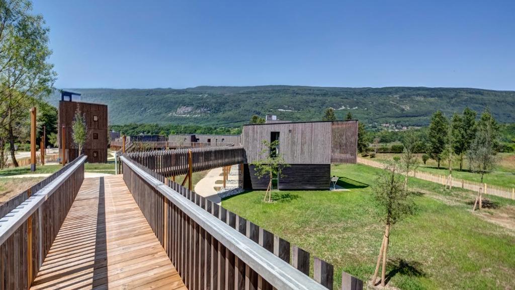 un puente de madera sobre un campo con una casa en Vacancéole - Le Village des Oiseaux, en Motz