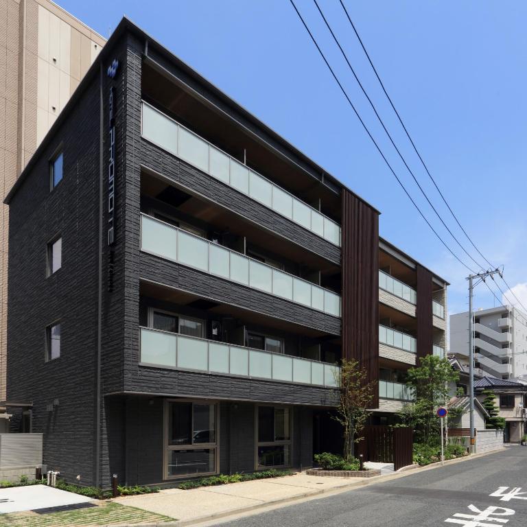 un bâtiment noir avec des fenêtres blanches sur une rue dans l'établissement HOTEL PROMOTE HIROSHIMA, à Hiroshima