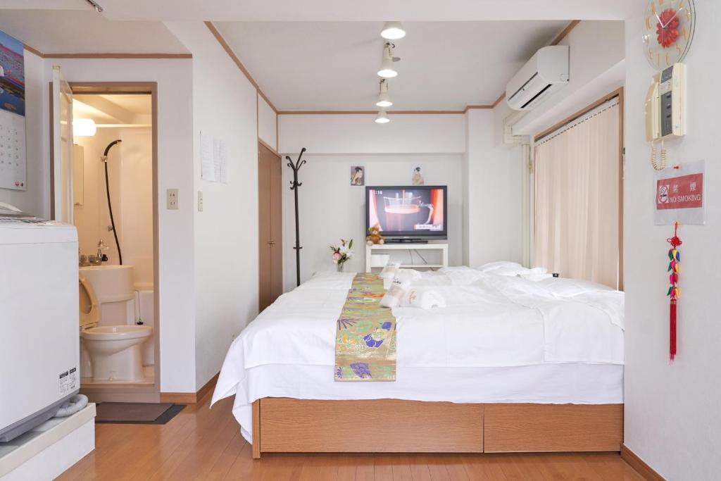 1 dormitorio con 1 cama blanca grande y baño en sakura house, en Tokio