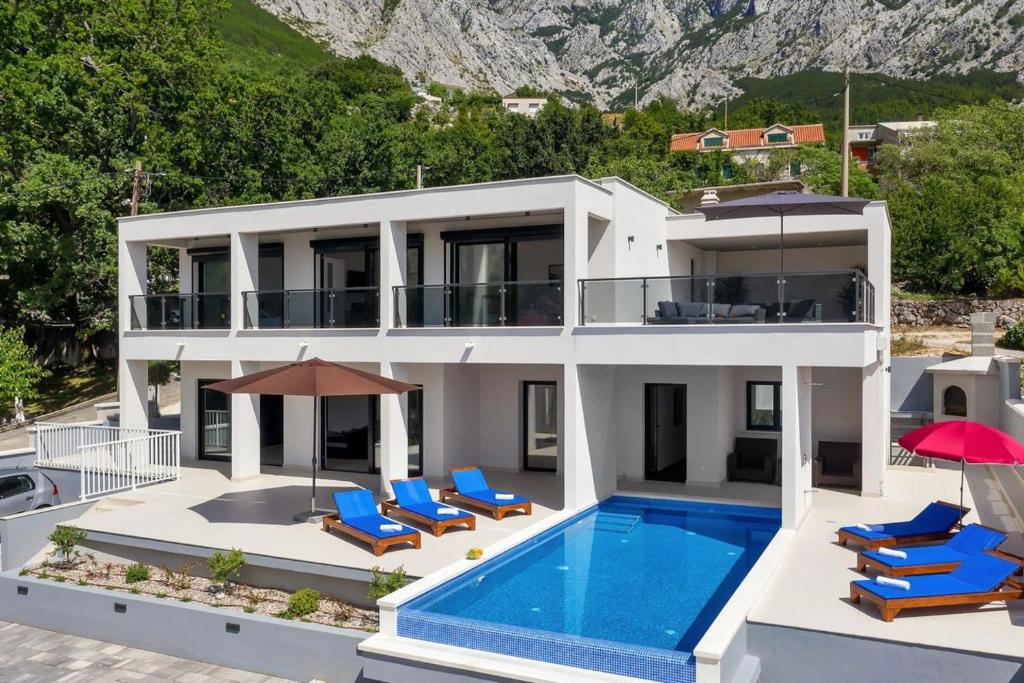 a large white house with a swimming pool and chairs at Holiday home E in Bast
