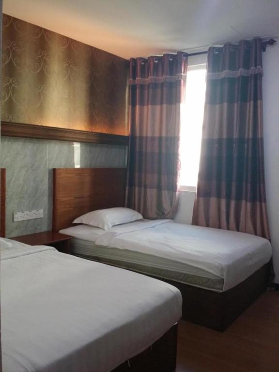 two beds in a room with a window at Maxi Inn in Bintulu