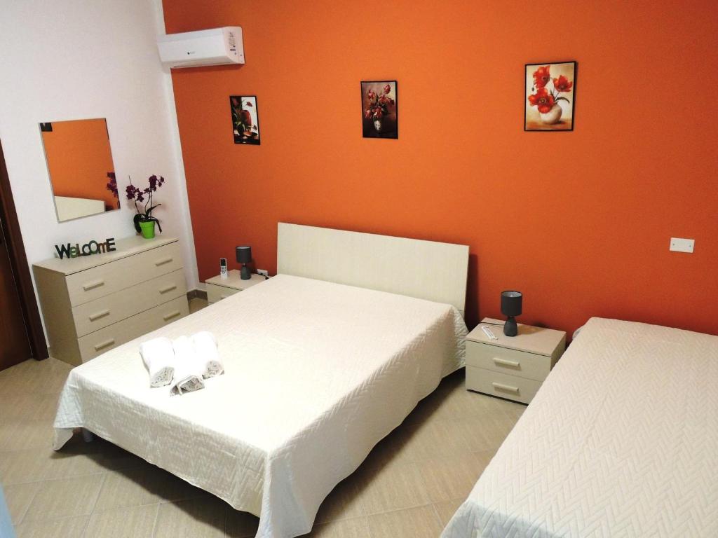 een slaapkamer met 2 bedden en een oranje muur bij FIORI E COLORI in Mazara del Vallo