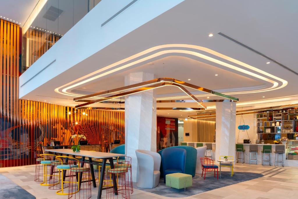 A colorful lobby lounge with casual tables, sofas, sculptural lighting and a visible reception or service area.