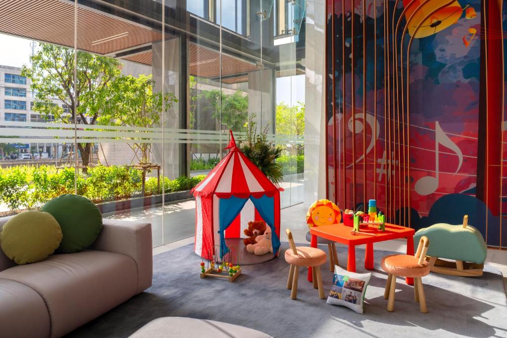 A sunlit lobby lounge with a children’s play corner beside large windows.