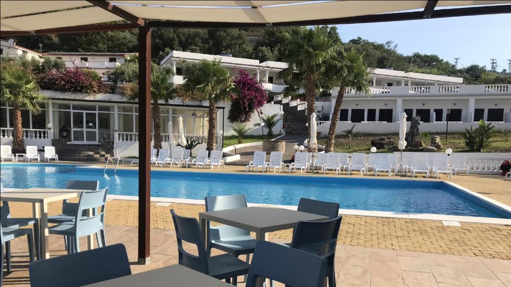 eine Terrasse mit Tischen und Stühlen neben einem Pool in der Unterkunft Hotel Diamond Residence in Diamante