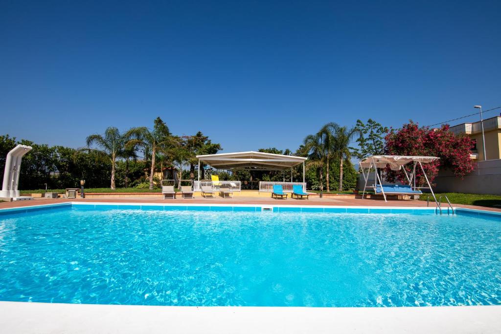 una grande piscina blu con sedie e ombrelloni di Villa Salvius a Scafati
