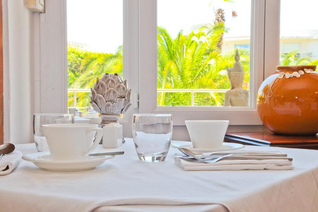 a table with a white table cloth and glasses and a window at Hôtel La Villa Cap d’Antibes in Juan-les-Pins