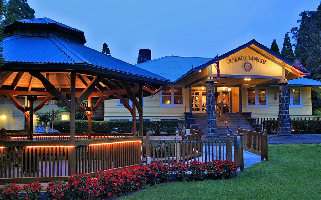 Kilauea Lodge and Restaurant في فولكانو: مبنى امامه سياج وزهور