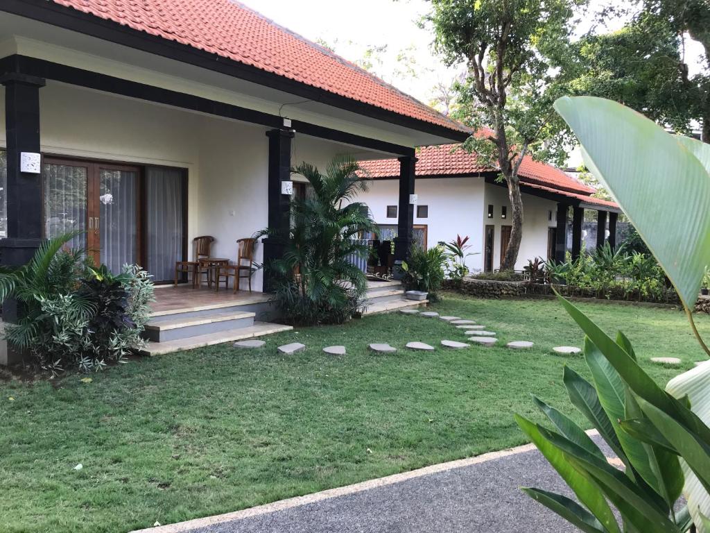 una casa con porche y patio de césped en villa pulu uluwatu bali, en Uluwatu