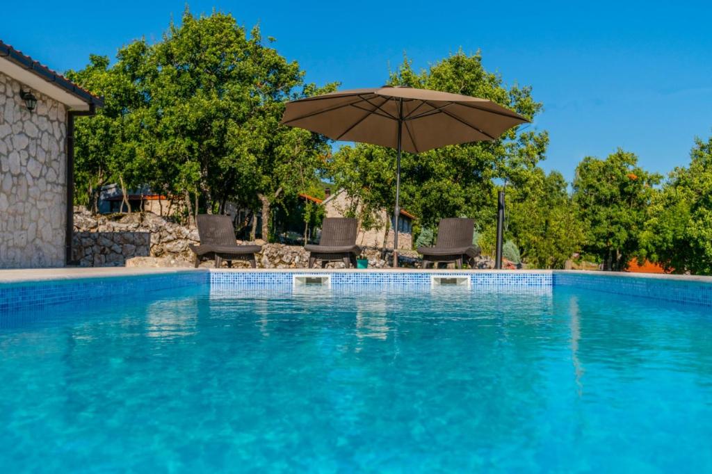 - une piscine avec un parasol et des chaises dans l'établissement Stone Villa Rafael, à Slivno