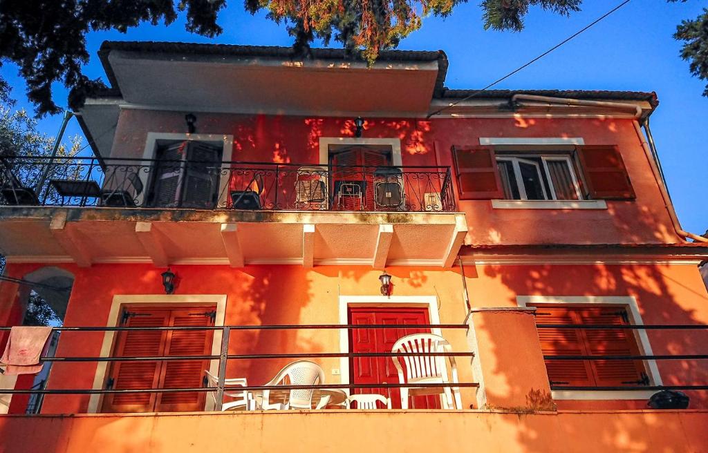 an orange building with chairs on a balcony at Iona Achilleion Appartments in Achílleion