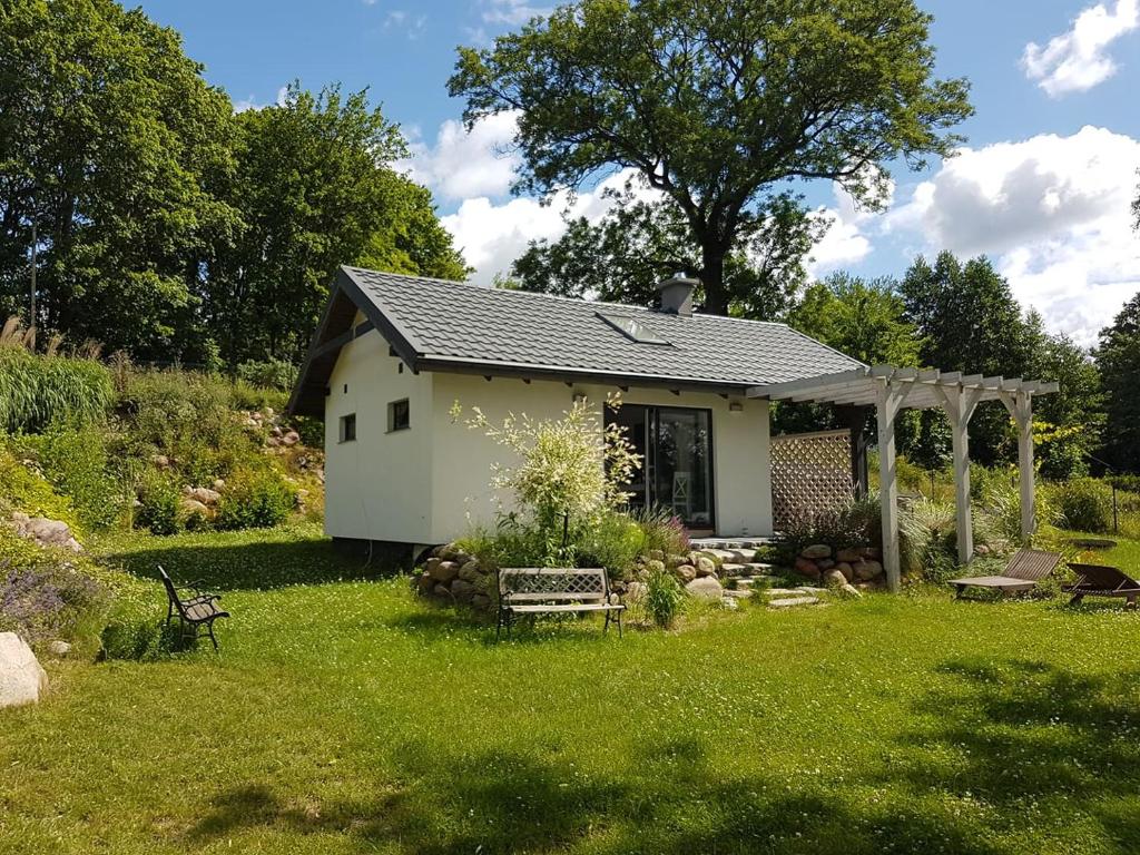 une petite maison dans une cour avec un jardin dans l'établissement Domek nad Jeziorem, à Zyndaki