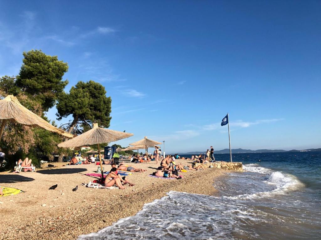 een groep mensen op een strand met parasols bij Villa Baronessa in Zadar