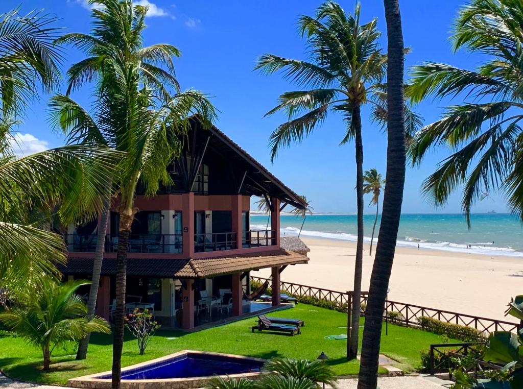 a house on the beach with palm trees at Dream Beach Cumbuco Oceanfront Apartments in Cumbuco