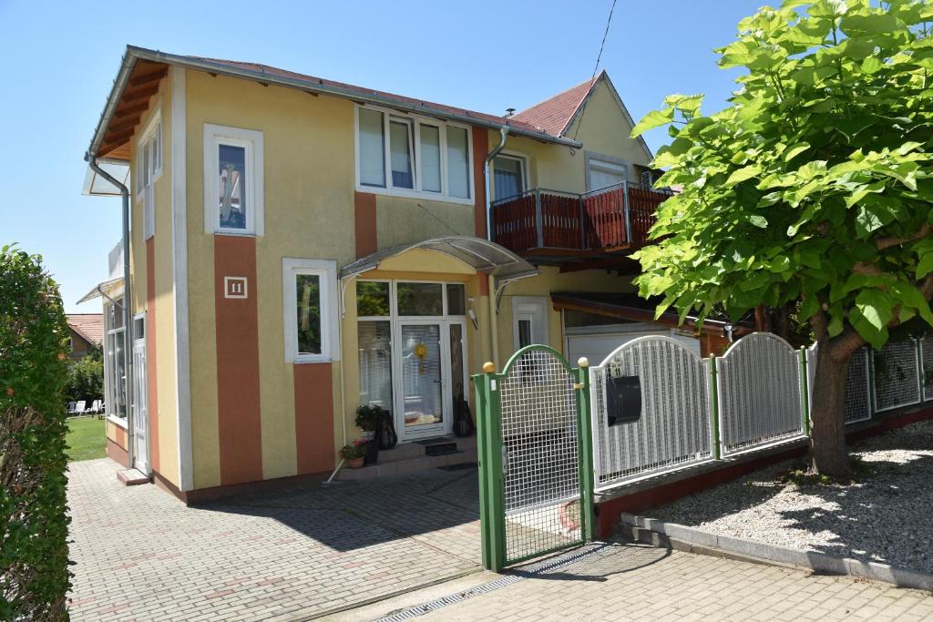 a house with a fence in front of it at Gyenesi Virág Apartman in Gyenesdiás