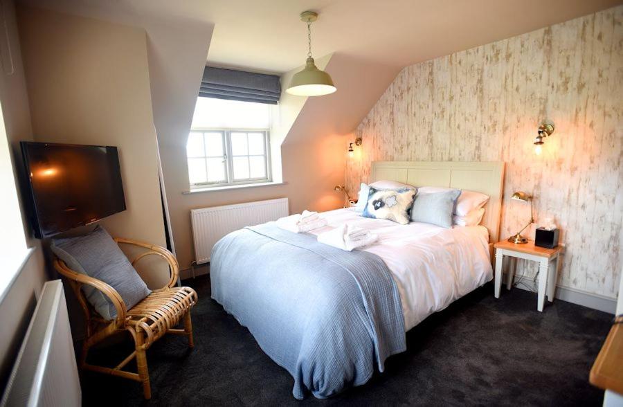 a bedroom with a large white bed and a tv at The Lifeboat Inn in Hunstanton