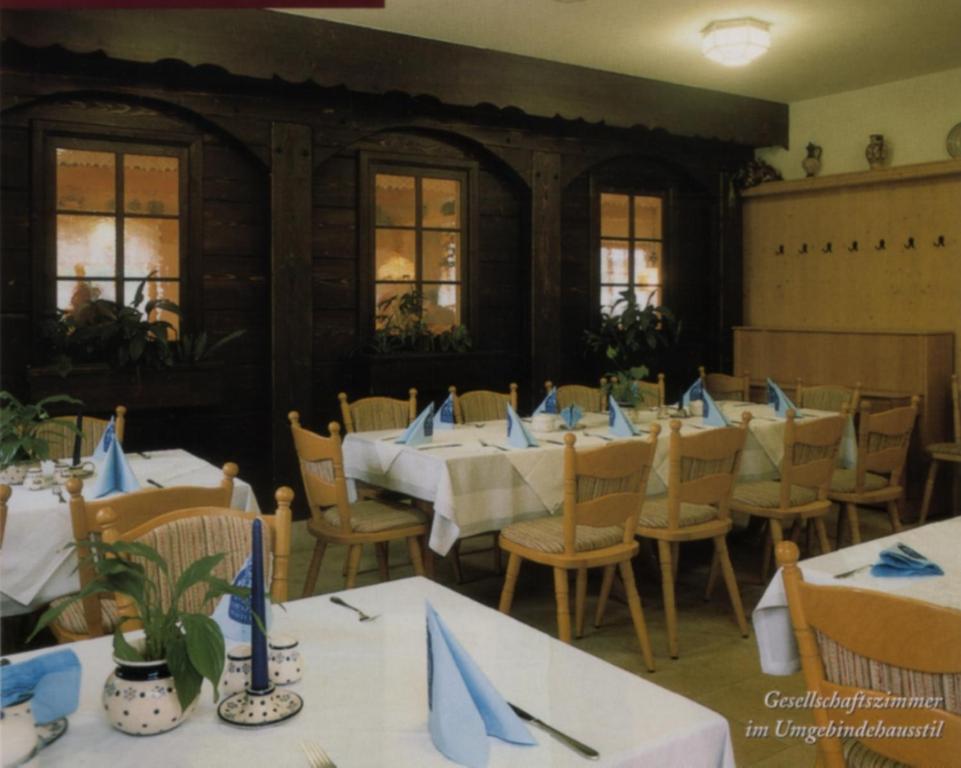 a dining room with tables and chairs with blue napkins at Rübezahlbaude in Großschönau