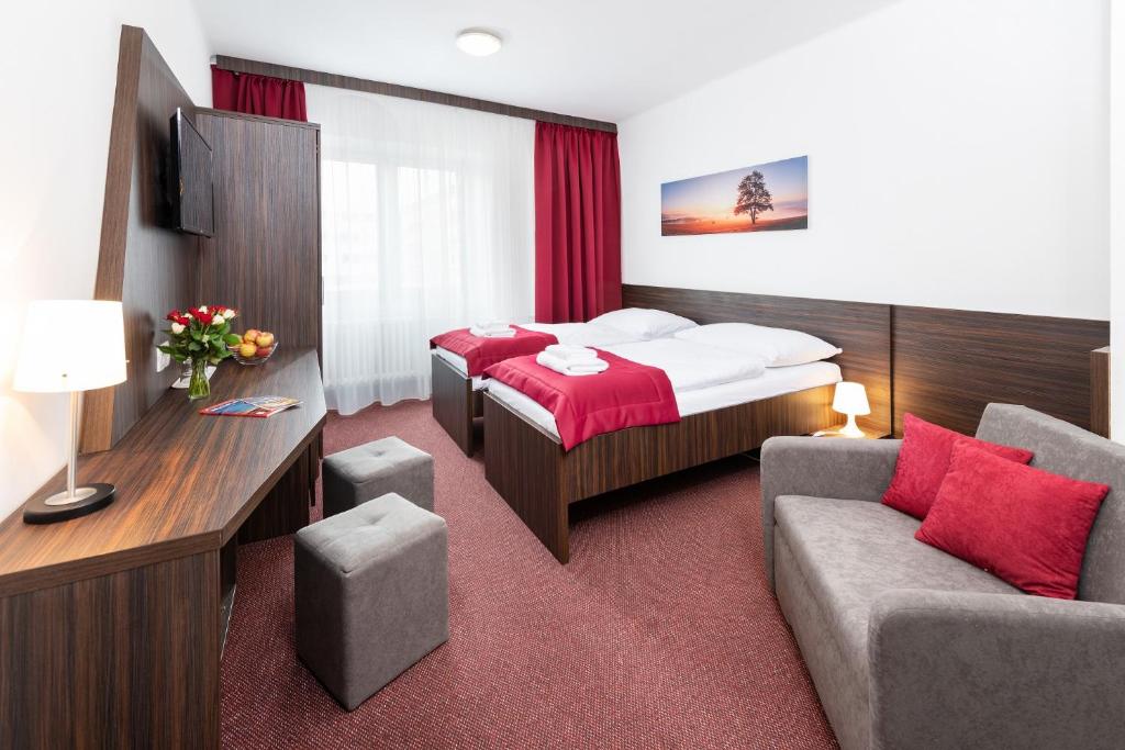Hotel Plus في براتيسلافا: غرفه فندقيه بسرير واريكه