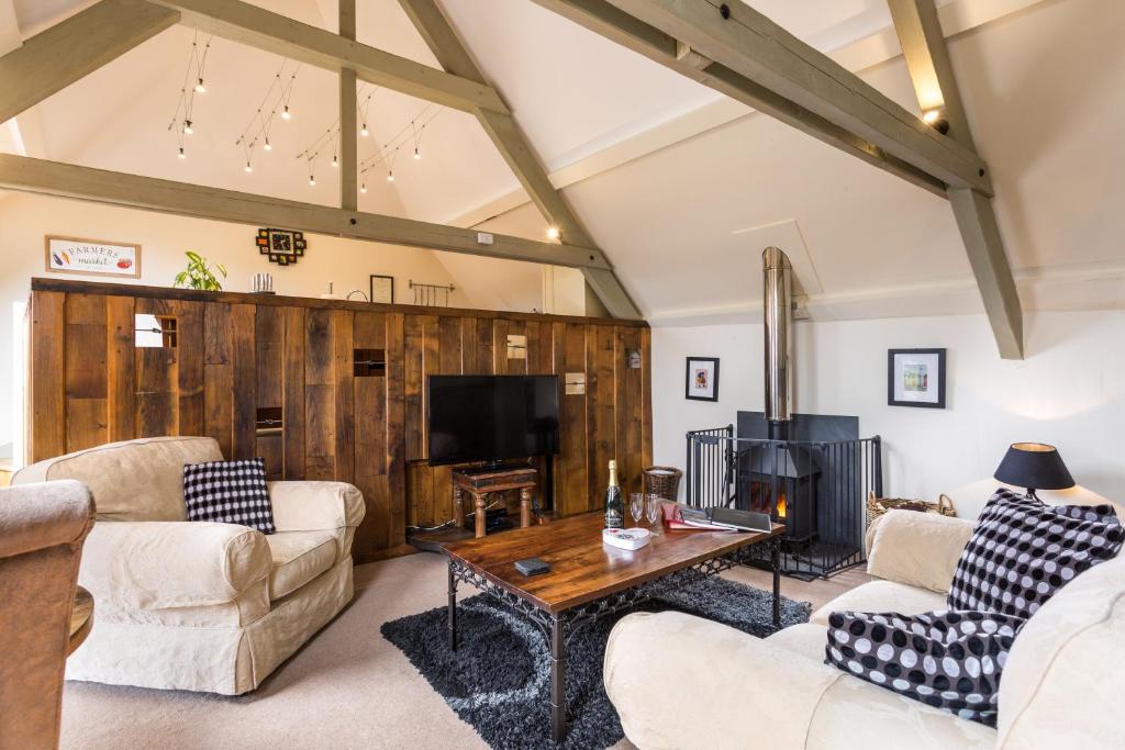 a living room with two couches and a tv at Red Doors Farm Cottages in Honiton