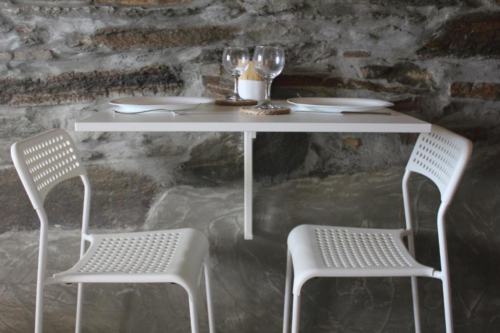 einen weißen Tisch mit zwei Stühlen, einem Tisch und zwei Gläsern in der Unterkunft Gaia Vacation Home in Agia Mavra