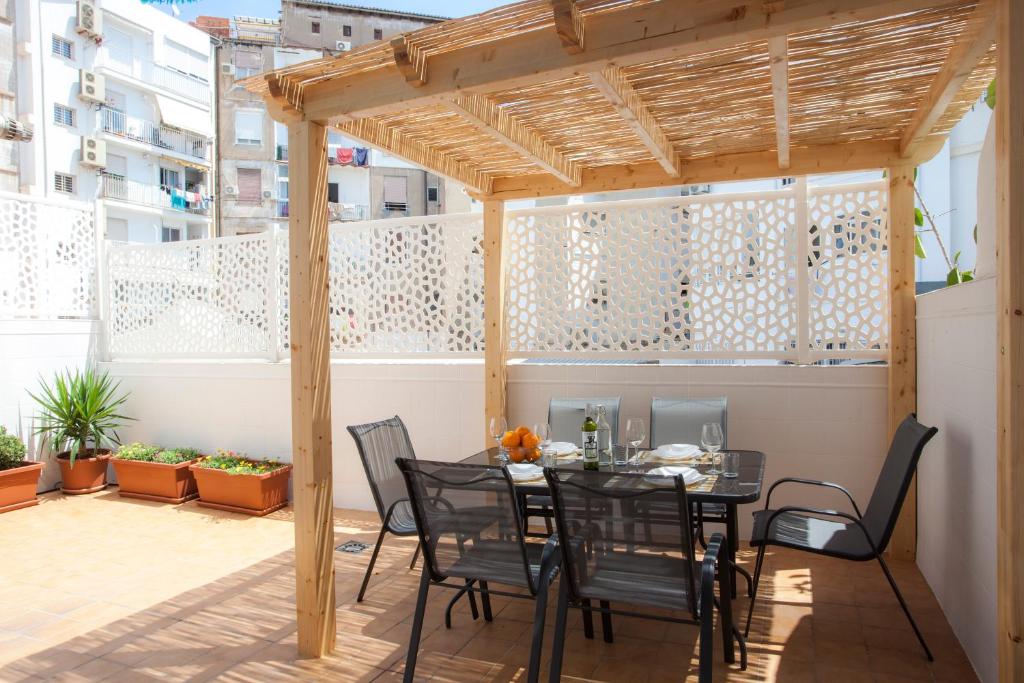 un patio con mesa y sillas bajo una pérgola de madera en Singularstays Ruzafa Terrace, en Valencia