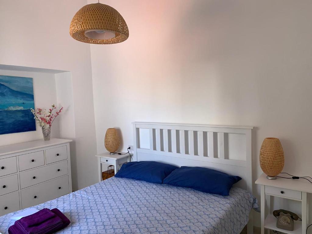um quarto com uma cama branca e almofadas azuis em MAMA' em Anacapri