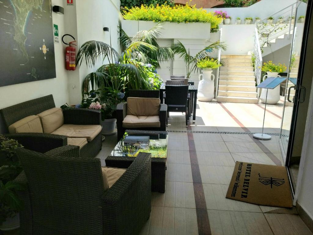 uma sala de estar com sofás, uma mesa e plantas em Hotel Belvir em Villasimius