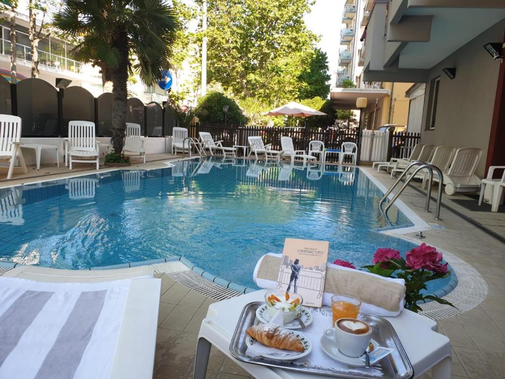 uma bandeja de comida sentada numa mesa ao lado de uma piscina em Hotel Giglio em Rimini