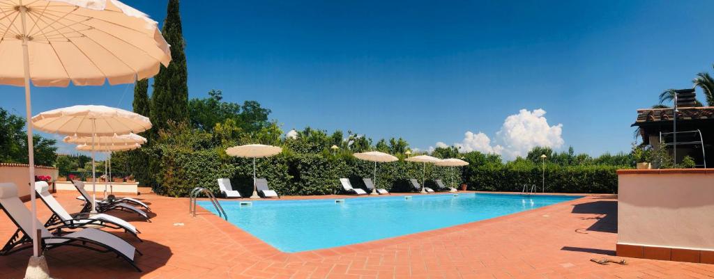 a swimming pool with chairs and umbrellas at Villa Lavinia B&B in Montescudaio