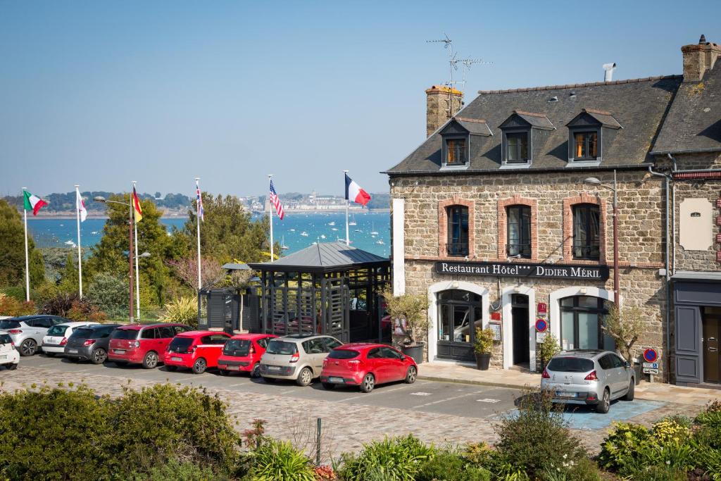 un estacionamiento con autos estacionados frente a un edificio en Restaurant Hotel Didier Méril en Dinard
