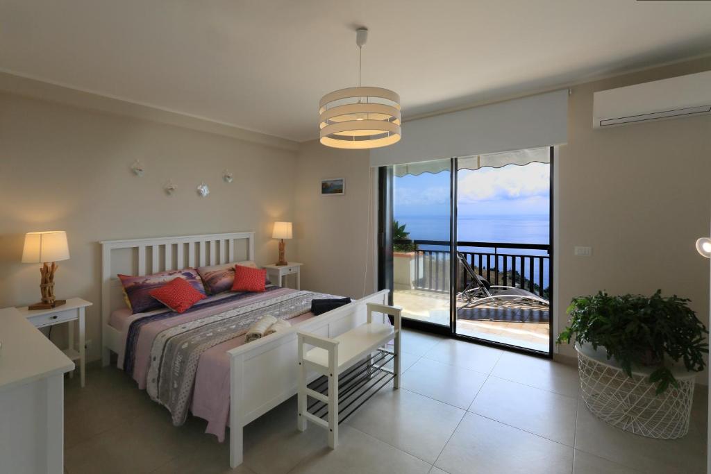 una camera da letto con un letto e un balcone con vista sull'oceano di Olimpia's House a Taormina