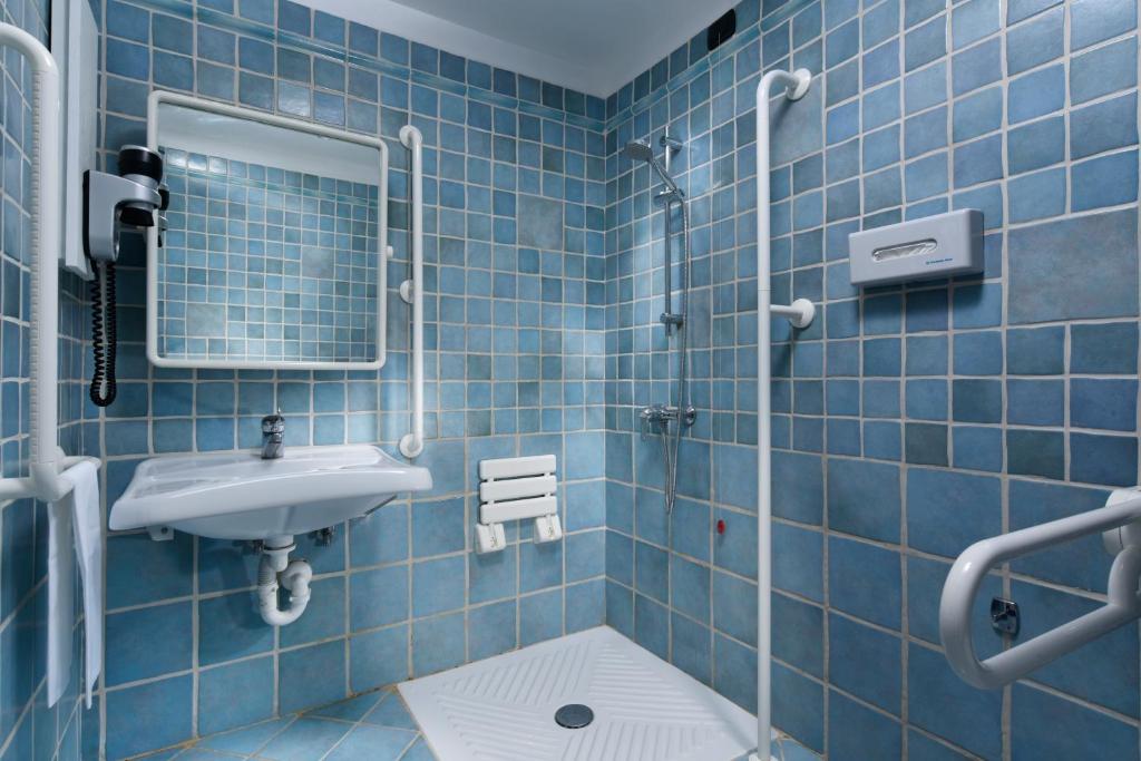 a blue tiled bathroom with a sink and a mirror at UNA HOTELS Capotaormina in Taormina