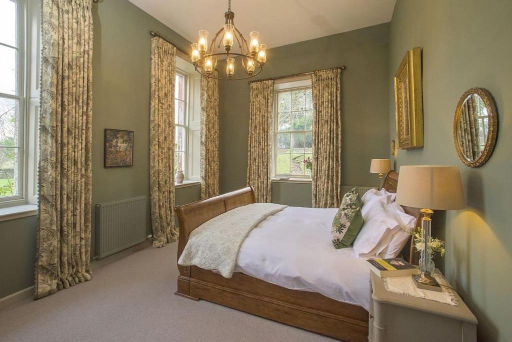 a bedroom with a bed and a chandelier at The Sculleries at Thirlestane Castle in Lauder