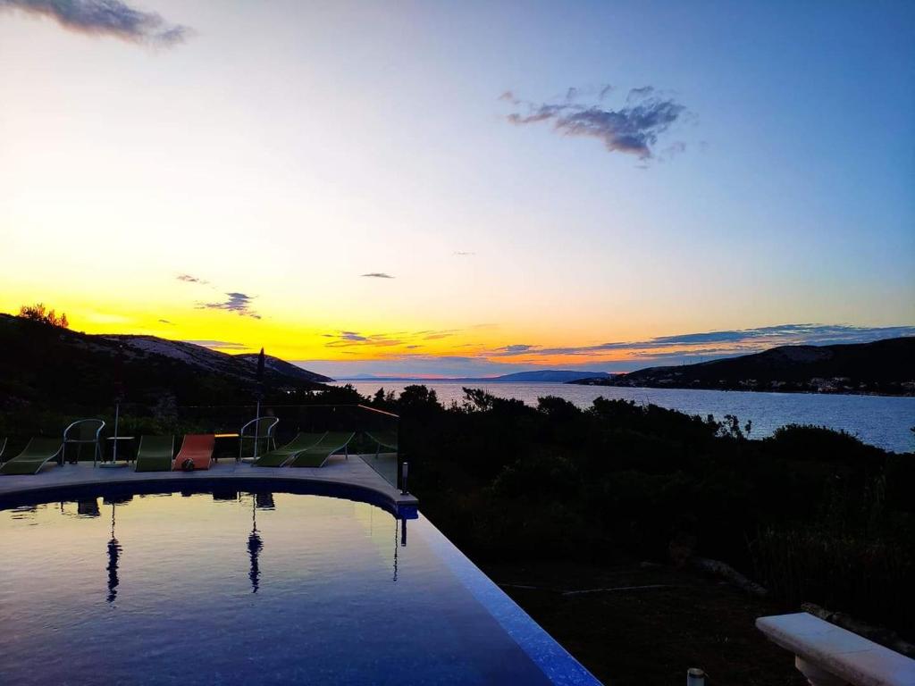 a swimming pool with the sunset in the background at Villa Vila in Novalja