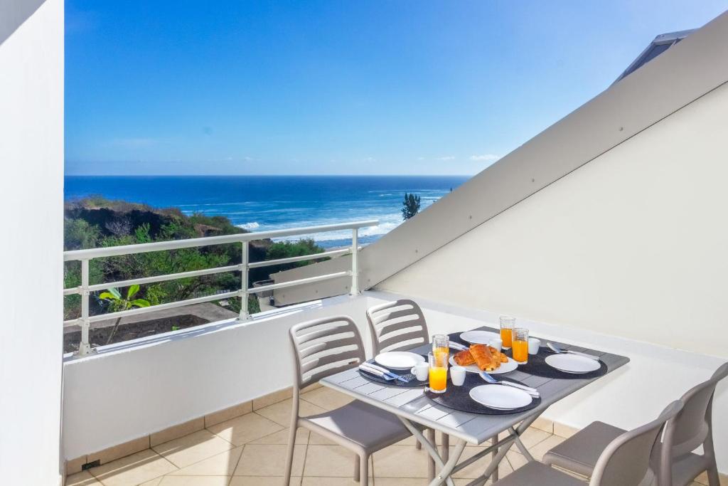 balcón con mesa, sillas y vistas al océano en Cap Homard - spacieux apt - magnifique vue mer -proche plage, en Saint-Gilles-les-Bains