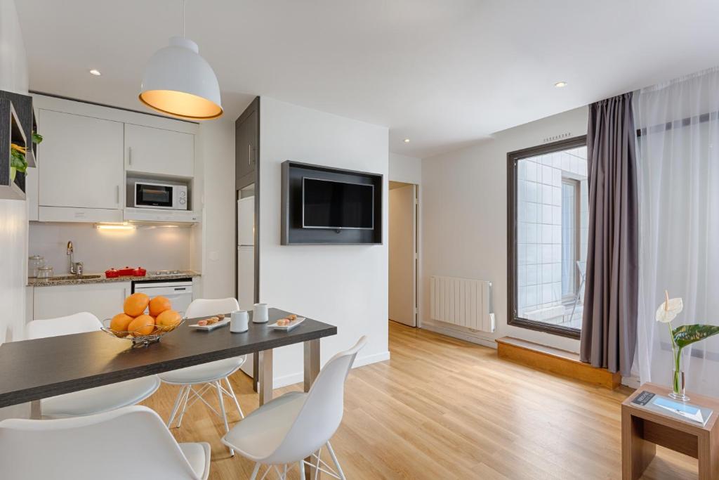 a kitchen and living room with a table and chairs at Citadines Austerlitz Paris in Paris