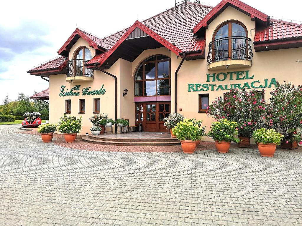 a hotel restaurant with potted plants in front of it at Zielona Weranda in Wieluń