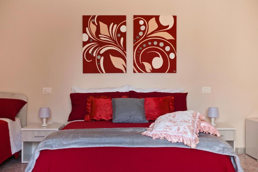 una camera da letto con un letto rosso e due dipinti alle pareti di B&B Mamma Carolina a Sanarica